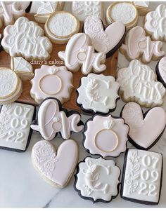 decorated cookies are arranged in the shape of hearts and letters on a white tablecloth