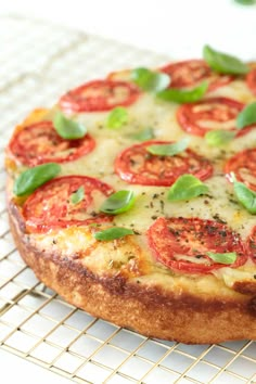 a pizza sitting on top of a cooling rack covered in cheese and tomato toppings