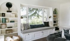 a living room filled with furniture and bookshelves next to a window covered in windowsills