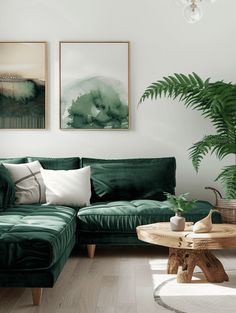 a living room with green velvet couches and paintings on the wall above it's coffee table