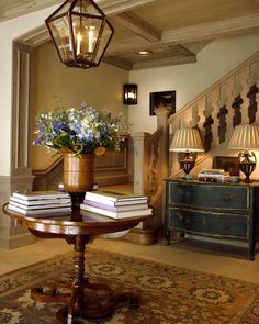 a table with some books on top of it next to a stair case and lamp