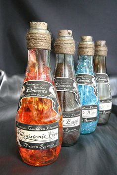 four bottles filled with different colored liquid sitting next to each other on a black surface