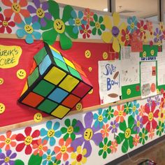 a classroom wall decorated with colorful flowers and smiley face stickers on the front, and a rubix cube in the middle