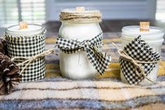 three mason jars tied with twine are sitting on a plaid blanket next to two pine cones