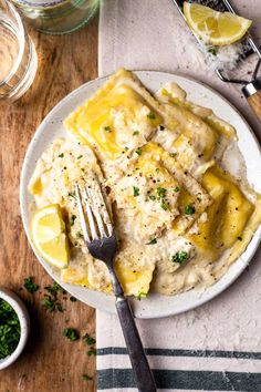 a white plate topped with ravioli covered in gravy and garnished with parsley