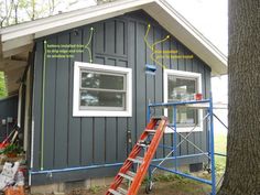 a ladder is in front of a house with windows and sidings on the side