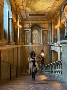 a woman is walking down the stairs in an old building