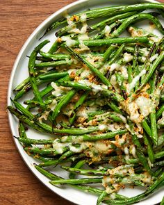 asparagus covered in sauce on a white plate sitting on a wooden table top