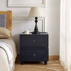 a nightstand with a lamp on top of it next to a bed