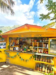 a small yellow shack with pineapples on the outside and shelves full of fruit