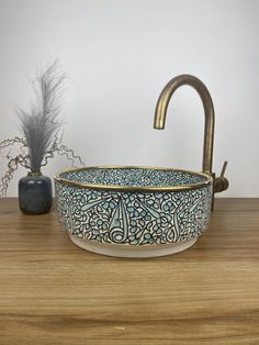 a sink that is sitting on top of a wooden table next to a potted plant