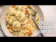 a white bowl filled with chicken and dumplings on top of a table next to a fork