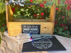 a wooden box with writing on it next to some pens and markeres in front of flowers