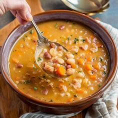 a person holding a spoon over a bowl of soup