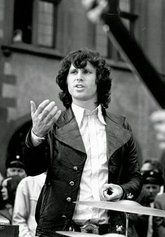 an old photo of a man standing in front of a crowd holding his hands up