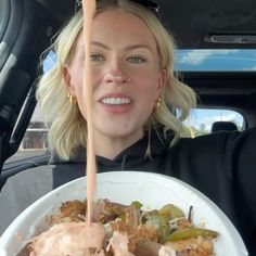 a woman holding a plate of food in her car