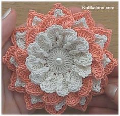 someone is holding a crocheted flower in their hand