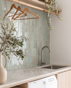 a washer and dryer in a kitchen with green tiles on the wall behind it