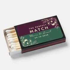 match box filled with matches on top of a white table next to a green and purple label