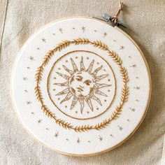 an embroidered sun and moon in a circular frame on a linen tablecloth with thread