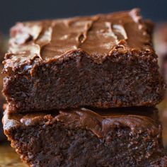 chocolate brownies stacked on top of each other with frosting in the middle and one piece cut off