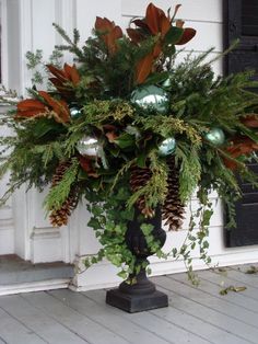 a vase filled with greenery sitting on top of a wooden floor next to a door