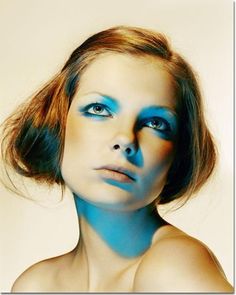 a woman with blue makeup is posing for the camera