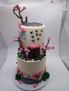 a three tiered cake decorated with flowers and trees