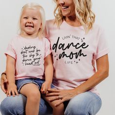 Dance mamas, we made the perfect shirt for watching your little dancer in class, dress rehearsal or a performance! Our dance mom life tee is available in pink and ash, and is soooo cute to match our dance your heart out tee for the littles! This design is also available in a match tote bag to carry around dance shoes, extra water, snacks and maybe a hairbrush for those ballet buns?? DETAILS Unisex sizing - aka mens sizing. If you want a looser fit, we recommend ordering your normal size or one up for an oversized fit. If you prefer a more fitted style, size down one. Tee - 52/48 Airlume combed and ringspun cotton/polyester. Side seams, shoulder to shoulder taping, tearaway label. Pink or Ash tee with black print Fitted Cotton T-shirt For Dance Class, Stretch Cotton T-shirt For Dance Class, Cotton Short Sleeve Tops For Dance Class, Fitted Pink T-shirt With Name Print, Fitted Cotton Tops For Dance Class, Cotton Summer Dance Tops, Casual Tops For Summer Dance Class, Casual Summer Tops For Dance Class, Cotton T-shirt With Relaxed Fit For Dance Class