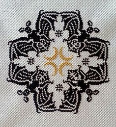 a cross stitch pattern with an orange star in the center on a white fabric background