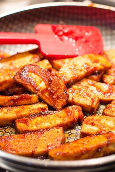 fried food in a frying pan with a red spatula