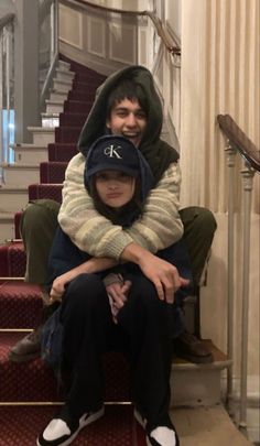 a man and woman sitting on the steps with their arms around each other