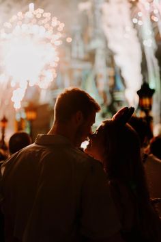 a man and woman standing next to each other with fireworks in the background