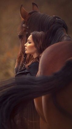 a woman standing next to a horse with her face close to the back of it