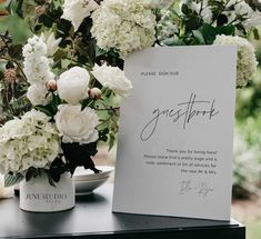 white flowers are in vases on a table next to a sign that says guestbook