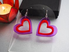 ❤️🔥 Show some love with these purple and red heart shaped earrings. These acrylic earrings are perfect for Valentine's day or your next Y2K look. They would make a wonderful gift for anyone who likes unique statement earrings.  ❤️🔥The dangle heart earrings are 1.75 inches wide and 1.72 inches long with a drop length of .5 inches. They are designed and handmade in my studio from clear purple and red 1/8th inch thick laser cut acrylic. The ear wires are sterling silver and come with a plastic ear nut back. All of my earrings are nickel free! ❤️🔥Take care: acrylic can be prone to scratching so do your best to treat these earrings like wearable art. Wipe clean with a lint-free cloth and water. ❤️🔥 I offer the cut out heart earrings in a few different color options! Check out my other listi Purple Heart Charm Earrings For Valentine's Day, Purple Heart Earrings For Valentine's Day, Laser Cut Earrings, Heart Shaped Jewelry, Heart Shaped Earrings, Laser Cut Acrylic, Acrylic Earrings, Red Heart, Heart Earrings