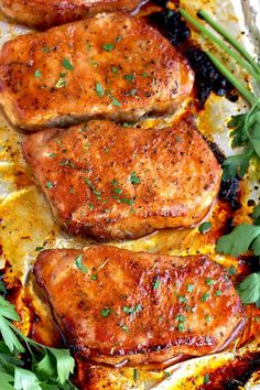 three pieces of meat sitting on top of a pan covered in parmesan cheese and herbs