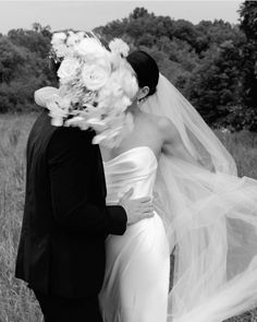 a bride and groom kissing in a field