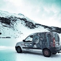 a van is parked in the snow with a mural on it's rear end