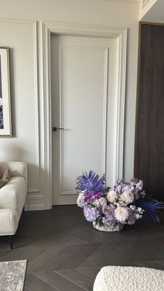 a vase with flowers in it sitting on the floor next to a couch and chair