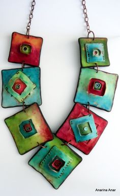 a colorful necklace is hanging from a chain on a white surface with red, green and blue squares