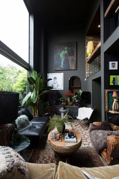 a living room filled with lots of furniture and plants on top of the couches