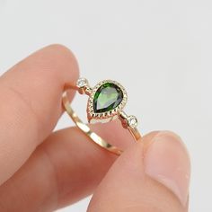 a person holding a ring with a green stone in it