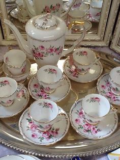 a silver tray topped with china cups and saucers