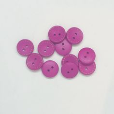 a bunch of pink buttons sitting on top of a white table