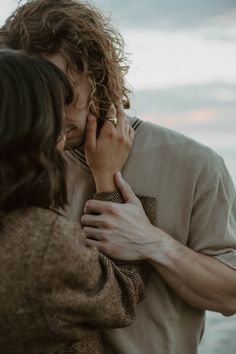 a man and woman standing next to each other with their hands covering their faces as they hug