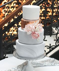 a three tiered wedding cake with pink flowers on the top and white frosting