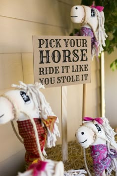 two stuffed horses sitting next to a sign that says pick your horse ride it like you stole it