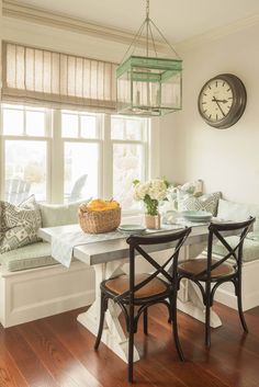 a kitchen table with two chairs and a bench in front of a clock on the wall