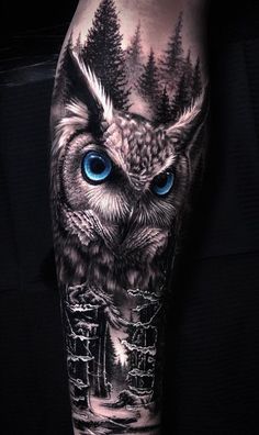 an owl with blue eyes and trees on his leg is seen in this tattoo design